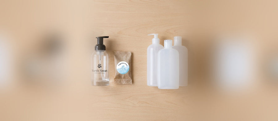 Swanflaske i glas og en refill-tablet ved siden af hvide plastflasker